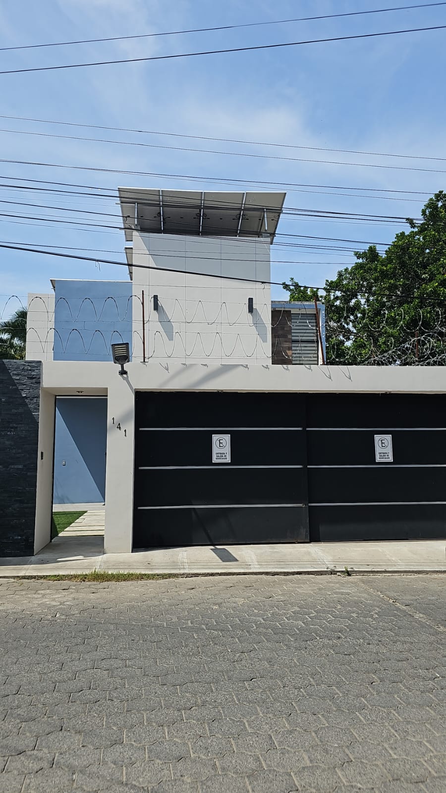 Fachada de Casa Samayac 141: portón negro y muro blanco